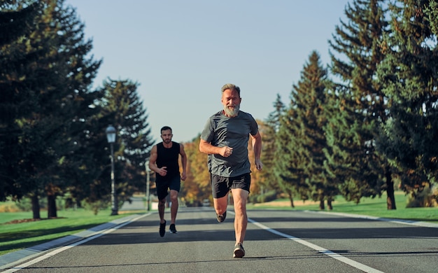 Die alten und jungen Sportler, die auf der Straße laufen