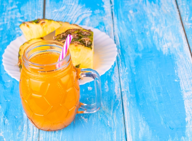 Die Ananas und Ananassaft auf dem blauen Brett