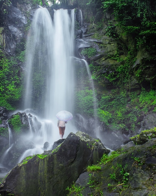 Die Ansicht eines Wasserfalls mit einer Person, die darunter steht, ist in Indonesien wirklich schön