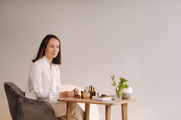 Die Aromatherapeutin sitzt in ihrem Büro, auf dem Tisch liegen ätherische Öle