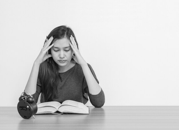 Die asiatische Frau der Nahaufnahme, die für sitzt, las ein Buch mit Belastungsgesichtsgefühl auf hölzerner Tabelle