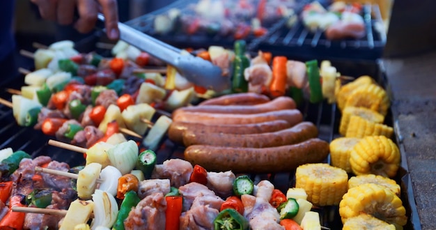 Die asiatische gruppe freunde, die gartengrill im freien haben, der mit alkoholischem bier lacht, trinkt auf nacht