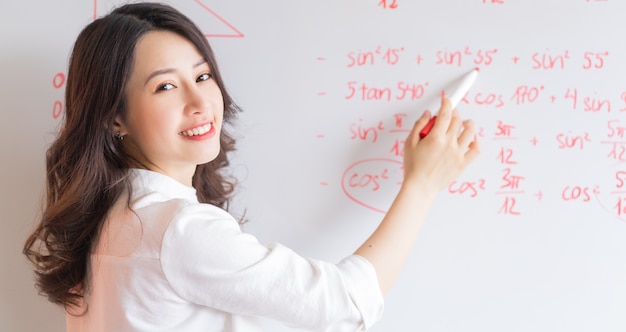 Die asiatische Lehrerin schreibt die Vorlesung an die Tafel