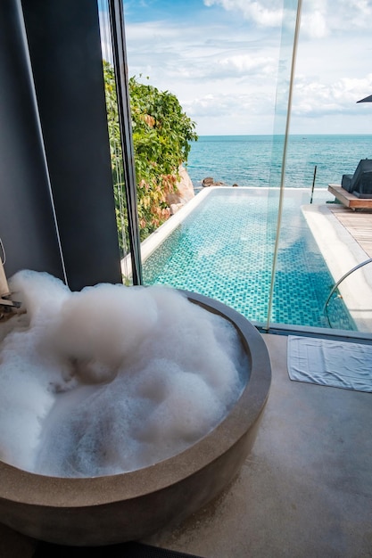 Die Badewanne mit Blasenschaum vor Ozeanhintergrund Sommerentspannung und Urlaubskonzepte