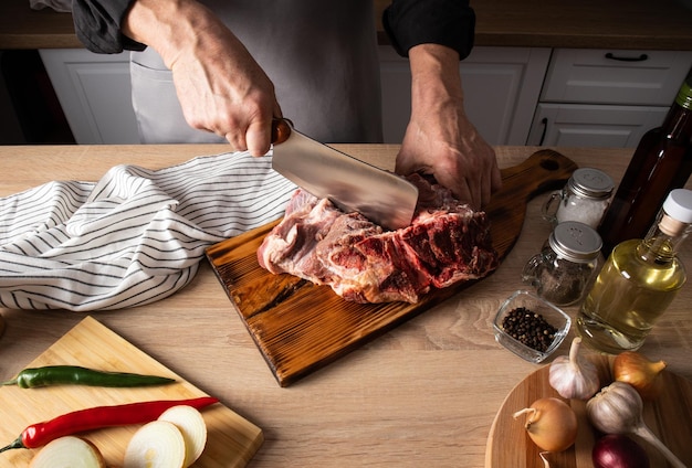 Die Bauernhände schneiden ein frisches Stück Fleisch auf einem Holzbrett auf der Arbeitsplatte Zutaten für das Kochen zu Hause richtige Ernährung