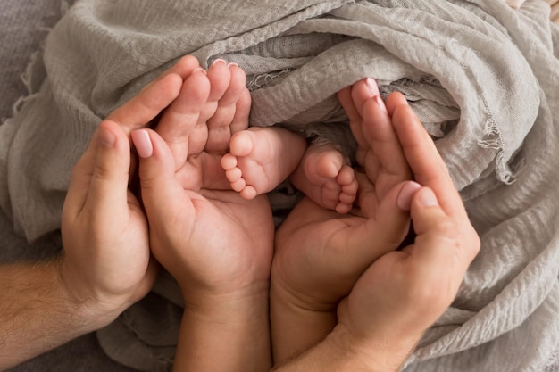 die Beine des Kindes in den Armen der Mutter und der Vater die Beine eines neugeborenen Babys