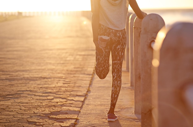 Die Beine strecken Zugeschnittenes Bild einer jungen Frau, die beim Joggen ihre Beine streckt