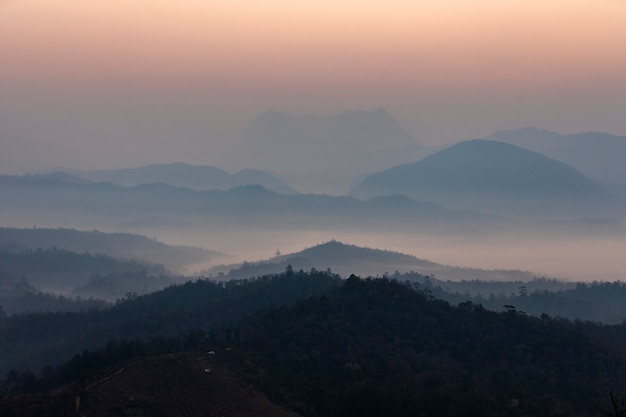 Die Berge sind in der Morgensonne von Nebel gesäumt.