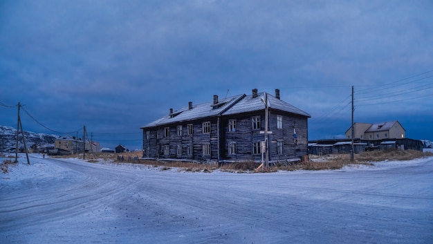 Die blaue Stunde. Vintage-Häuser auf schneebedeckten arktischen Hügeln. Altes authentisches Dorf Teriberka. Kola Halbinsel. Russland.