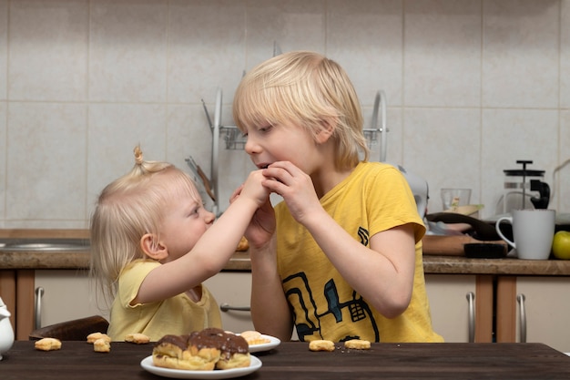 Die blonde jüngere Schwester verwöhnt ihren Bruder mit Süßigkeiten