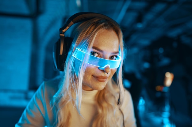 Die Blondine spielt ein Computerspiel Blogger in futuristischer Neonbrille