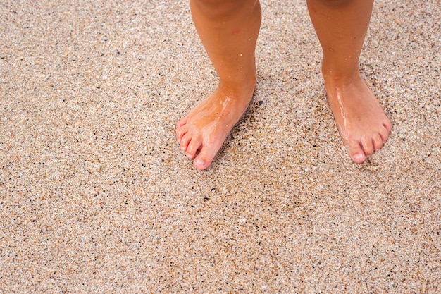 Die bloßen Füße der Kinder stehen auf dem Sandstrand.