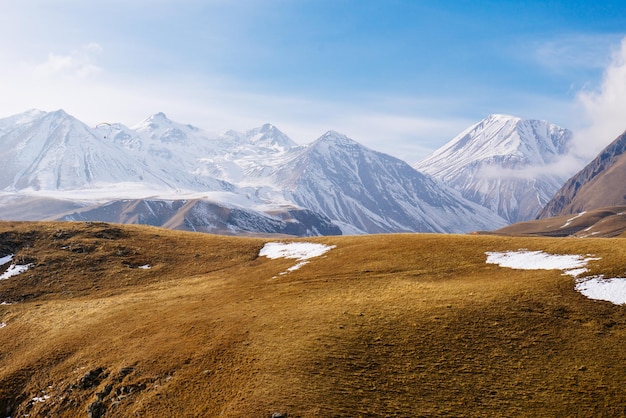 Die bogenförmige Natur und Landschaft die hohen Berge sind mit weißem Schnee bedeckt die grenzenlosen gelben Felder