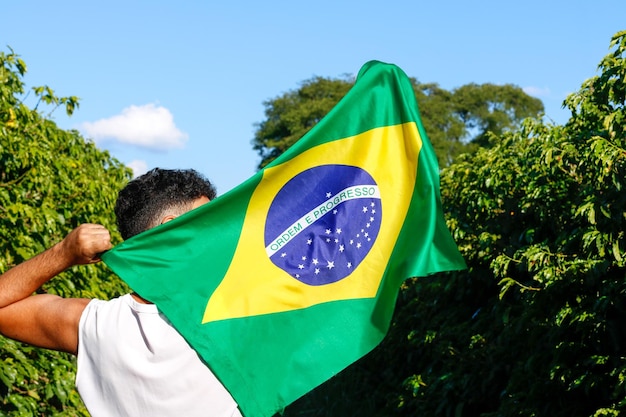 Die brasilianische Flagge im Wind halten