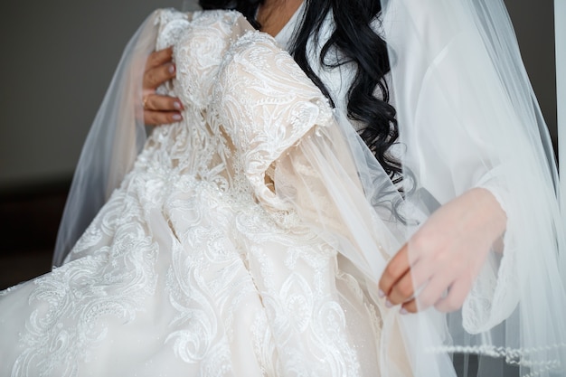 Die Braut hält am Hochzeitstag ein weißes Kleid in den Händen.