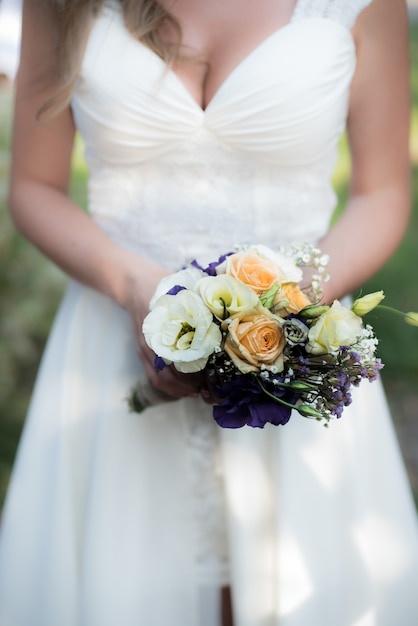 Die Braut hält einen Hochzeitsstrauß mit lila Blumen