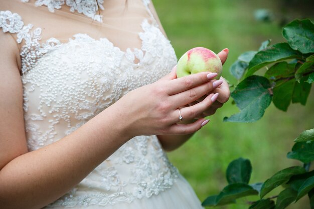 Die Braut hält einen reifen roten Apfel in den Händen