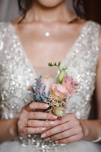 Die Braut hält in der Hand Nahaufnahme des Bräutigams Knopfloch Blumen mit Rosen und Grün und Grün Vorbereitungen der Braut Hochzeit Morgen Konzept