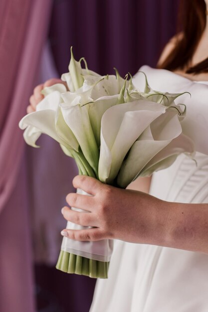 Foto die braut hält mit einem bräutigam einen hochzeitsbouquet in ihren händen