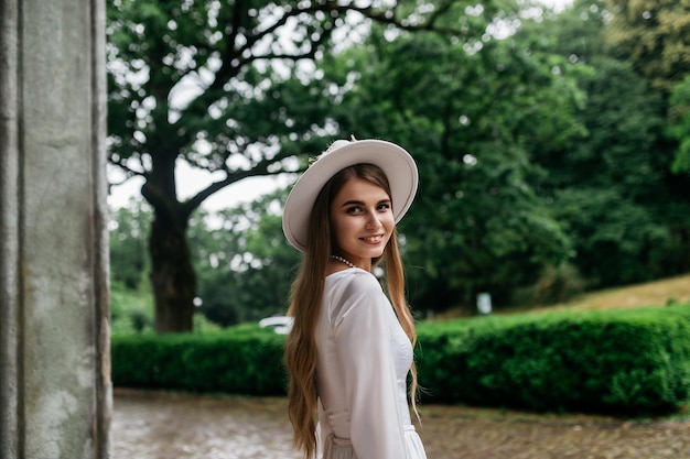 Die Braut in einem Hut und einem Blumenstrauß Porträt einer Braut in einem weißen Kleid Porträt der Braut Junges Mädchen in einem weißen Brautkleid und Hut mit einem Blumenstrauß