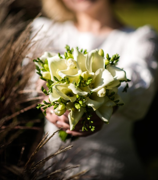 Die Braut in einem weißen Hochzeitskleid hält einen Strauß weißer Blumen Pfingstrosen Rosen Hochzeit Braut und Bräutigam Delicate Willkommensstrauß Schöne Dekoration von Hochzeiten mit Blättern