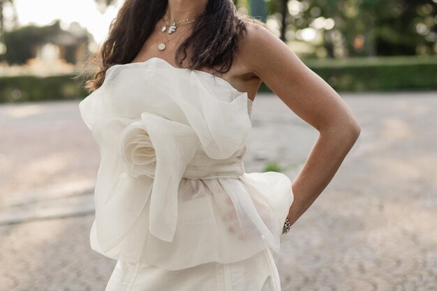 Die Braut in einem weißen Hochzeitskleid im Park bei Sonnenuntergang