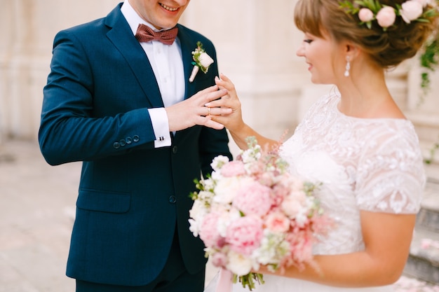 Die Braut legt einen Ring an den Finger des Bräutigams und hält während der Hochzeit einen Blumenstrauß in den Händen