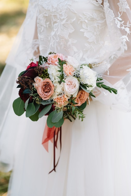 Die Braut steht in einem weißen Hochzeitskleid mit einem Blumenstrauß