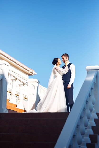 Die Braut und der Bräutigam auf Treppenstufen Elegantes, stilvolles junges Paar genießt einander auf der Treppe