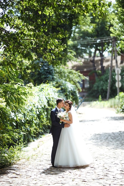 Die Braut und der Bräutigam gehen zusammen im Park Hübsche Braut und stilvoller Bräutigam Hochzeitstag Ehe