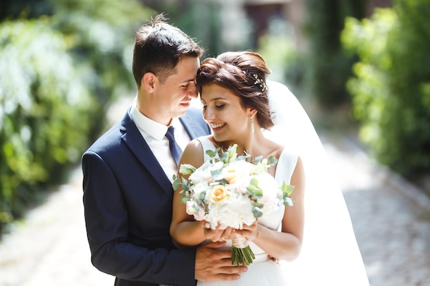 Die Braut und der Bräutigam gehen zusammen im Park Hübsche Braut und stilvoller Bräutigam Hochzeitstag Ehe