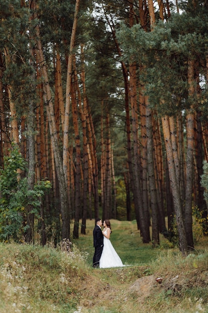 Foto die braut und der bräutigam laufen durch ein hochzeitsfoto-shooting im wald