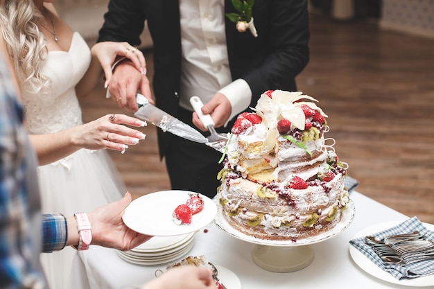 Die Braut und der Bräutigam schneiden die Hochzeitstorte.