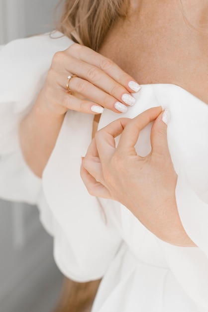 Die Braut zieht ein Kleid für die Hochzeit an Nahaufnahme der Hände