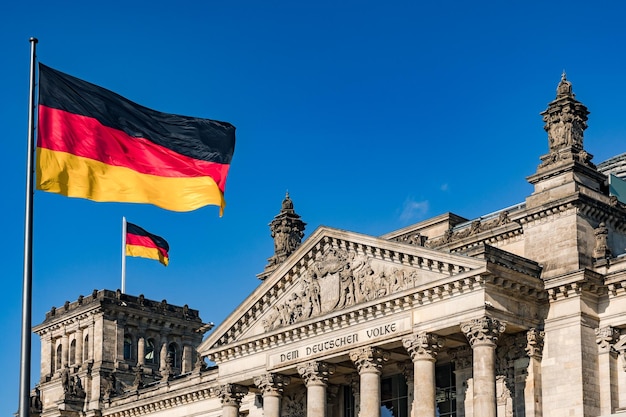 Die Bundesflagge vor dem beeindruckenden Reichstag in Berlin als Symbol der Demokratie