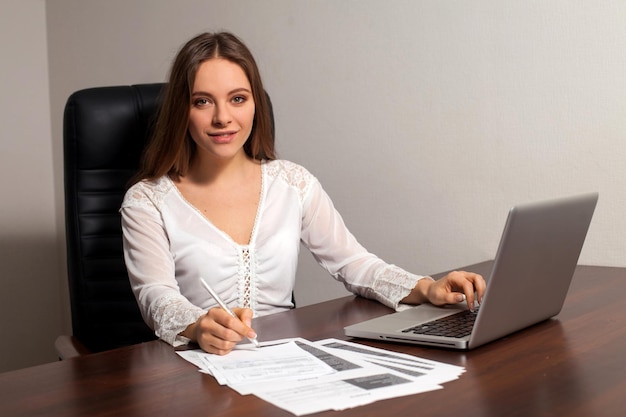 Die Chefin sitzt auf dem Stuhl und erledigt ihre Arbeit im Büro