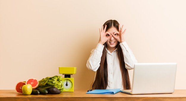 Die chinesische Frau des jungen Ernährungswissenschaftlers, die mit ihrem Laptop zeigt OK arbeitet, unterzeichnen vorbei Augen