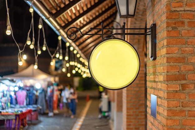 Die Circle Yellow Lightbox hat an der Wand vor dem Backsteinmast in einem Vintage-Einkaufszentrum mit Wolfram-Ambiente aufgehängt