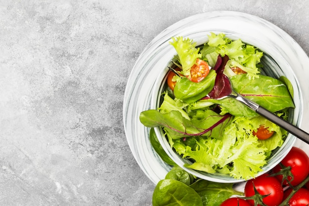 Die diätetischen Mischgrünsalat- und -kirschtomaten in einer Schüssel auf einem hellen Hintergrund