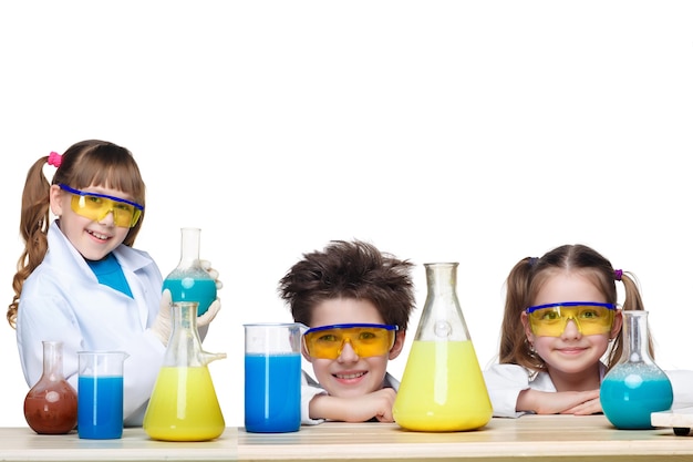 Die drei süßen Kinder als Chemiker im Chemieunterricht machen Experimente einzeln auf weißem Hintergrund