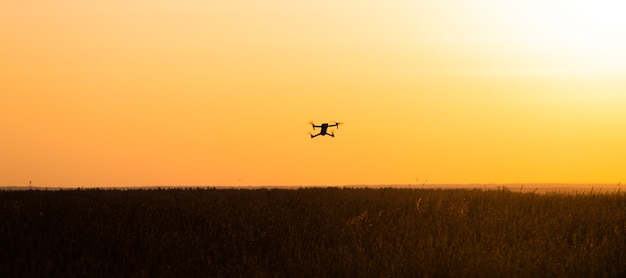 Die Drohne ist bei Sonnenuntergang im Flug. Videoaufnahmen von oben. Ein Artikel über die Wahl eines Quadrocopters. Vor- und Nachteile der Drohne.