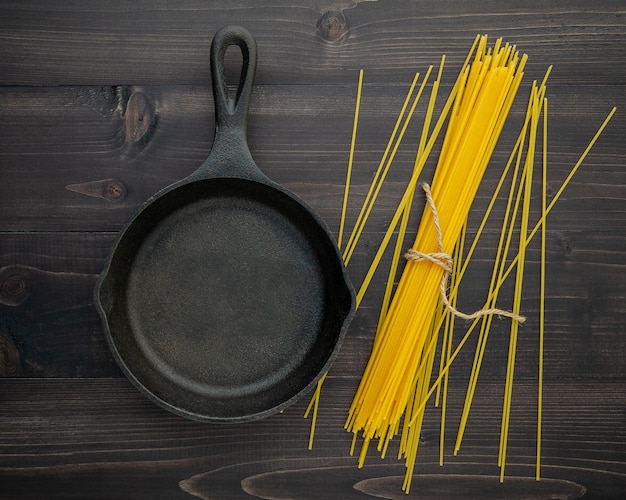 Die dünnen Spaghettis auf schwarzem hölzernem Hintergrund.