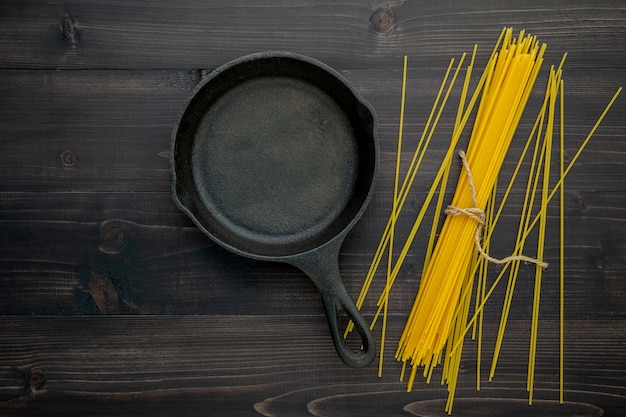 Die dünnen Spaghettis auf schwarzem hölzernem Hintergrund.