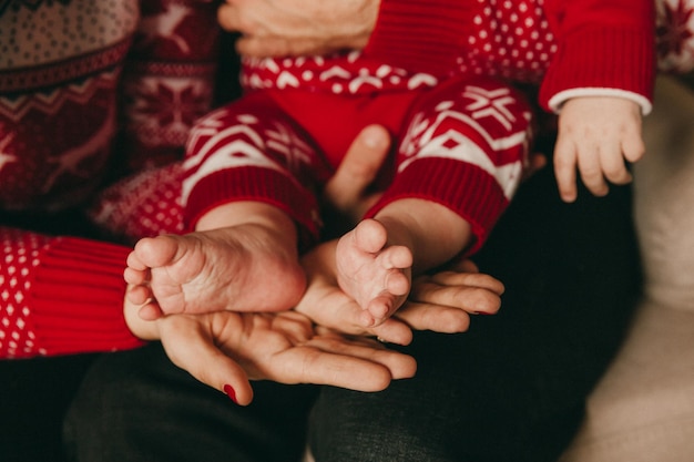 Die Eltern halten die Beine des Neugeborenen in den Händen. Mama und Papa halten die Beine des Babys. ... Babyfüße in den Händen von Mutter und Vater. Eltern und Kind.