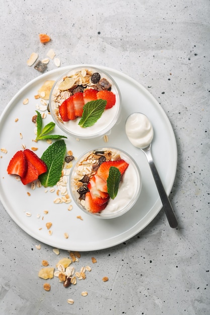 Die Erdbeere und das Müsli im Joghurt. Glasschalen mit Sahne und Erdbeeren. Draufsicht