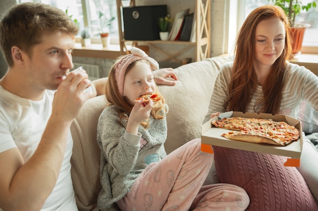 Die Familie, die zu Hause schöne Zeit miteinander verbringt, sieht glücklich und fröhlich aus