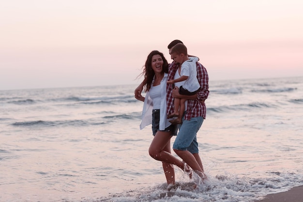 Die Familie genießt ihren Urlaub, während sie mit ihrem Sohn selektiven Fokus am Sandstrand entlang spazieren