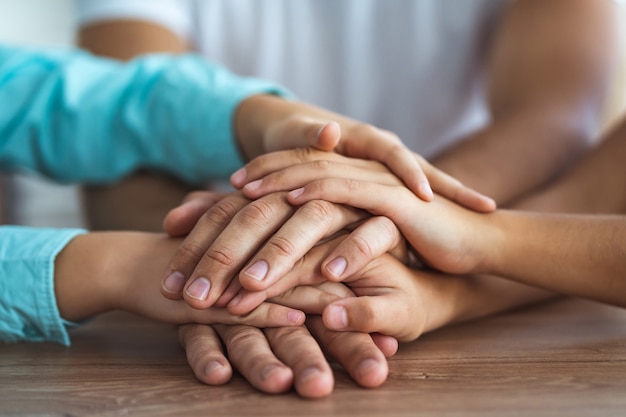 Die Familie hält am Tisch Händchen