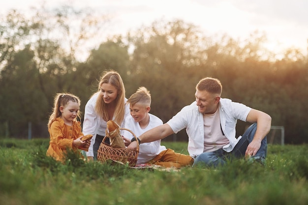 Die Familie sitzt auf dem grünen Gras und hat im Sommer zusammen ein Wochenende im Freien