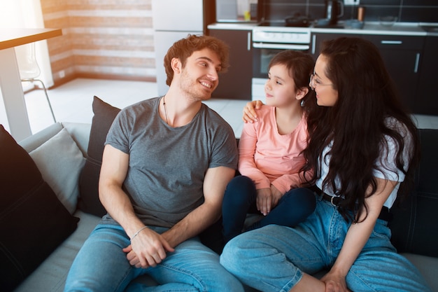 Die Familie sitzt auf dem Sofa. Glückliche Zeit zusammen. Eltern und Tochter oder älterer Bruder und Schwester und jüngere Schwester haben Spaß miteinander